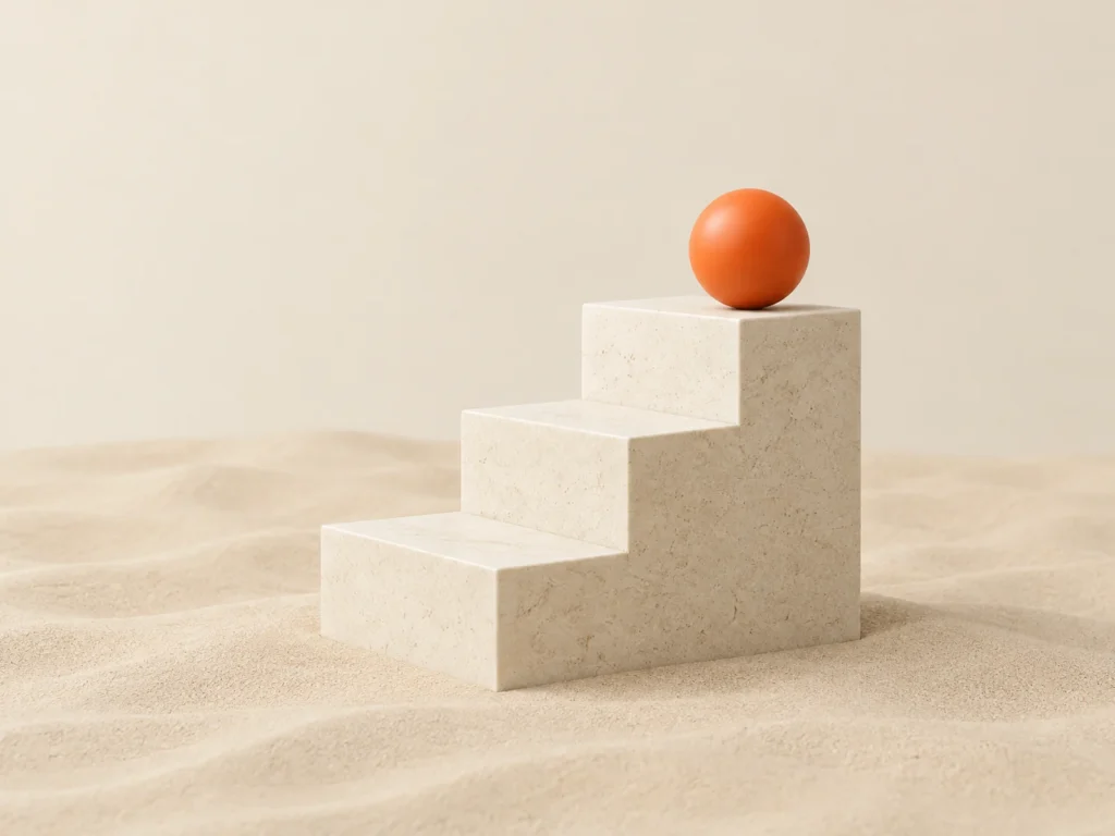An orange ball at the top of a short stone staircase set in sand