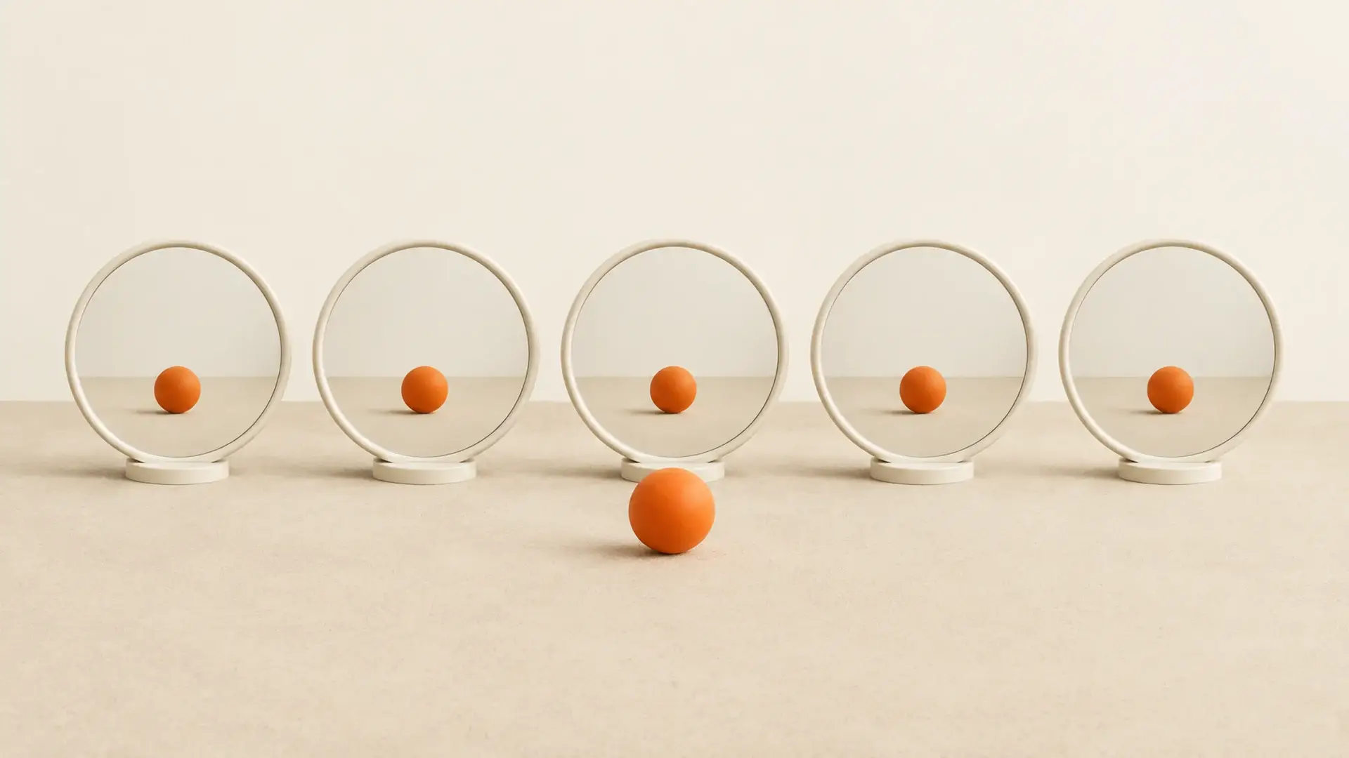 Five round mirrors each reflecting an orange ball, with one real orange ball in front
