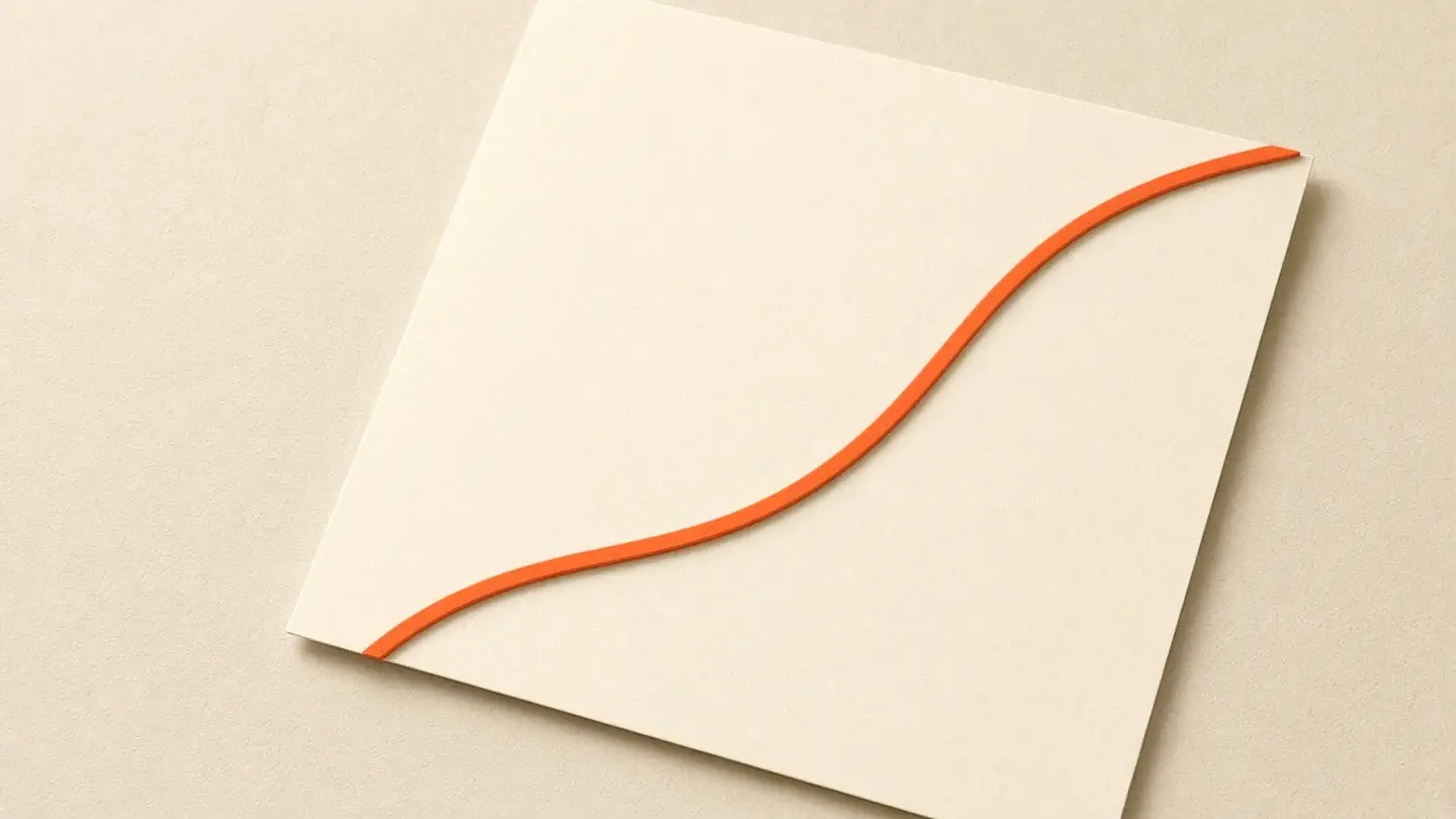 A cream sheet of paper on a sand surface with one orange line running across it.